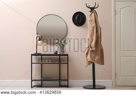 Console Table, Clothes Rack And Mirror On Beige Wall In Hallway. Interior Design