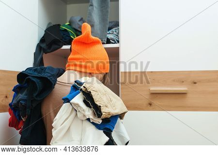 Boy Holding Pile Of Dirty Clothes. Untidy Clutter Clothing Closet. Messy Home Kid's Room. Home Chore