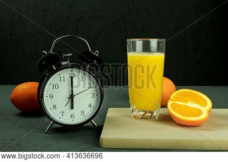 Alarm Clock At Which Six O'clock In The Morning. Black Clock And Orange Juice. Time - 6:00 Am And Re