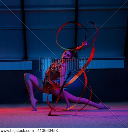 Young Graceful Girl Gymnast Isolated Over Colored Background In Neon Light