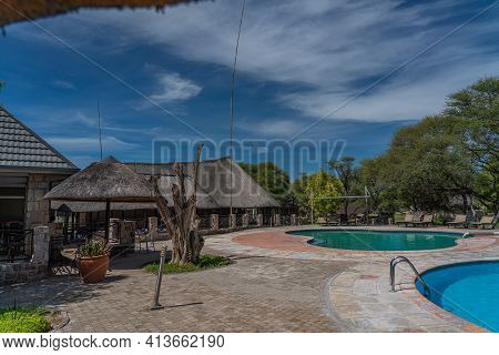 Okaukuejo, Namibia - January 14, 2020 : Okaukuejo Resort With Thatched Roof Houses And Pool In Etosh