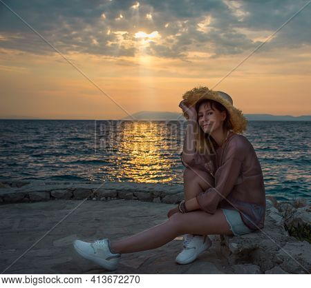 Woman Resting By The Sea In The Evening And Enjoying The Sunset