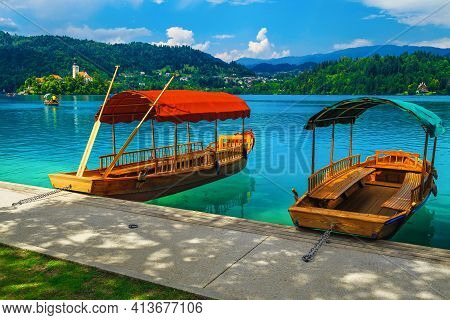 Famous Traditional Wooden Pletna Boat Moored At The Pier. Rowing Pletna Boat On The Lake Bled And Pi