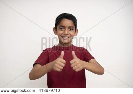 Young Indian Kid Showing Thumbs Up Into The Camera While Smiling. Small Kid Education Concept.
