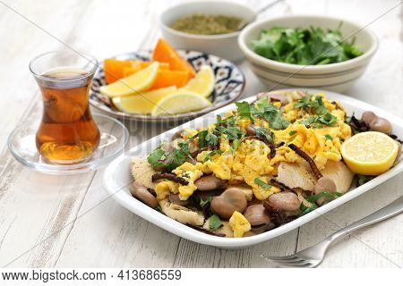 iraqi breakfast; boiled dried broad beans and scrambled eggs over pieces of flatbread