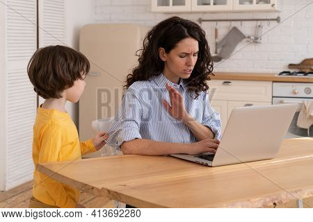 Nervous Mom Sits By The Table At Home Office During Lockdown, Working On Laptop, Asks Not To Make No