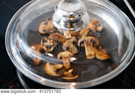 View From Above Of Frying Pan Covered With Glass Lid Of Fresh Mushrooms