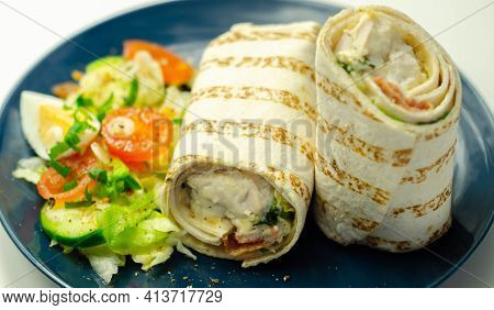 Tortilla Wrap With Chicken And Beechwood Smoked Bacon Served With Mix Salad On The Blue Plate