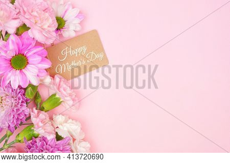 Happy Mothers Day Gift Tag With Side Border Of Pink And White Flowers. Top View On A Pink Background