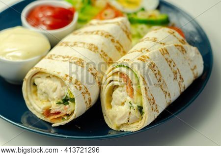 Tortilla Wrap With Chicken And Beechwood Smoked Bacon Served With Mix Salad On The Blue Plate