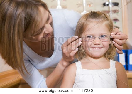 ผู้หญิงแว่นตากับสาวที่ Optometrists ยิ้มพยายาม