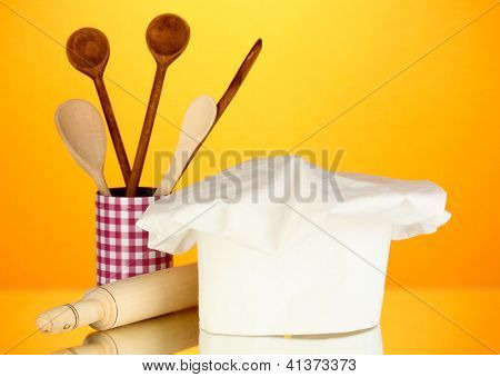 Kochmütze mit Löffel und Federballschläger auf orange Hintergrund