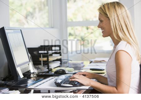 Woman In Home Office With Computer Smiling