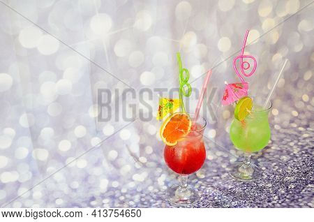 Two Glasses Of Citrus Juices With Ice And Slices Of Grapefruit And Lime On A Gray Abstract Backgroun