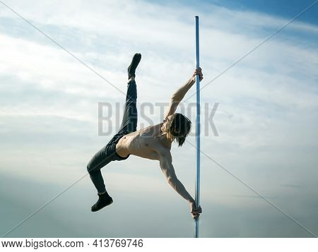 Young Strong Man Pole Dancing. Pole Dance Sport. Pole Dance Training Of Young Man Dancer On Blue Sky