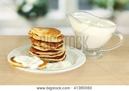 หวาน pancakes บนแผ่น ด้วยครีมเปรี้ยวบนโต๊ะในห้องครัว