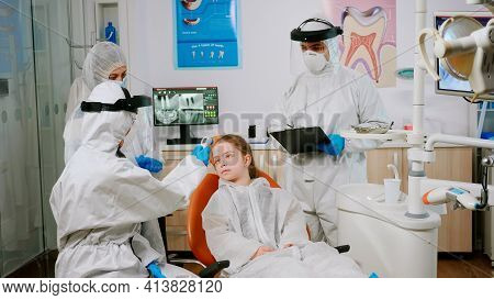 Stomatologist In Potective Suit Measuring Kid Patient Temperature