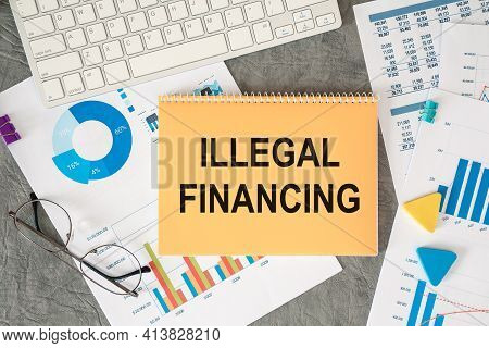 Illegal Financing Is Written In A Document On The Office Desk With Office Accessories.