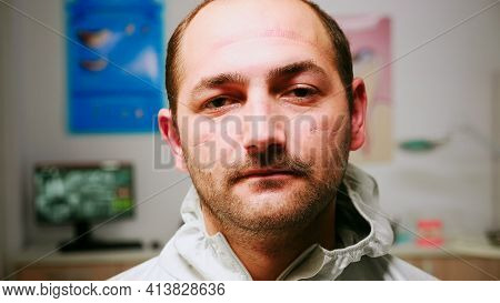 Close Up Of Tired Pediatric Stomatologist Man Taking Off Face Shield