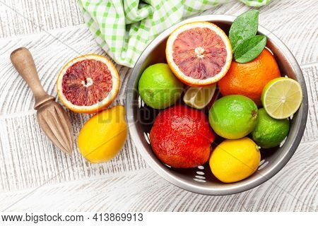 Various fresh citrus fruits in colander. Bood orange, lime, lemon. Top view flat lay