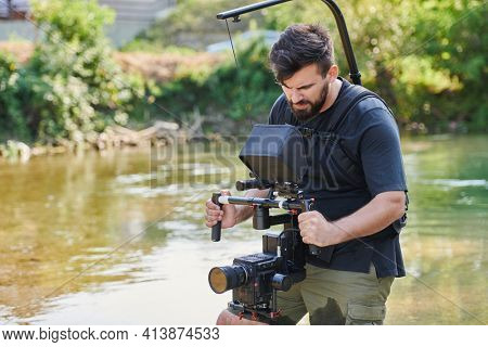 a professionally equipped cameraman shoots in the water surrounded by beautiful nature.