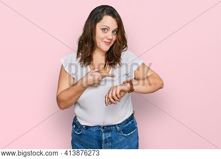 Young plus size woman wearing casual white t shirt in hurry pointing to watch time, impatience, upset and angry for deadline delay 