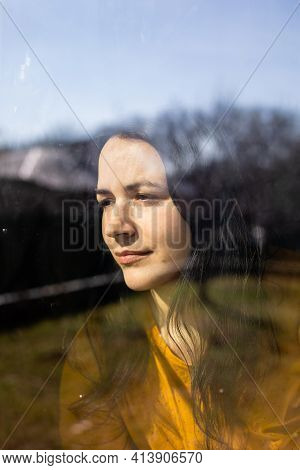 The Young Woman Is Looking Through The Window On Sunny Day