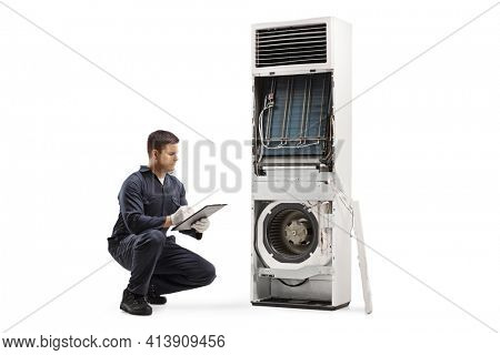 Repairman inspecting a self standing air conditioner with removed cover for service isolated on white background