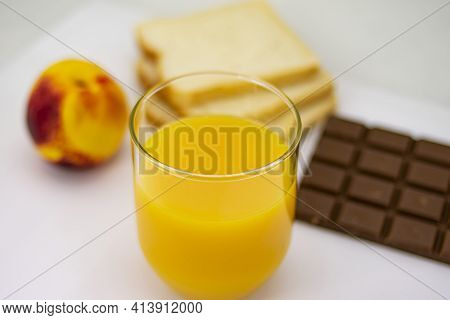 Breakfast Consisting Of Natural Orange Juice, Ripe Peach, White Bread And Milk Chocolate