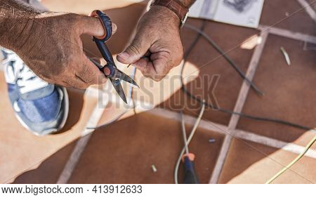 A Man Uses His Hands And Scissors To Strip Wire And Make Electrical Connections