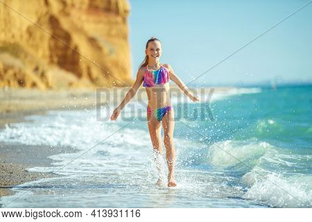 Child Girl Runs On The Waves. Rest By The Sea, Fun Outdoors. High Quality Photo.
