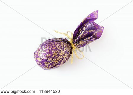 Close-up Egg Or Ellipse Shaped Candy Wrapped In Puprle And Golden Paper With Bow. Gift, Souvenir, So