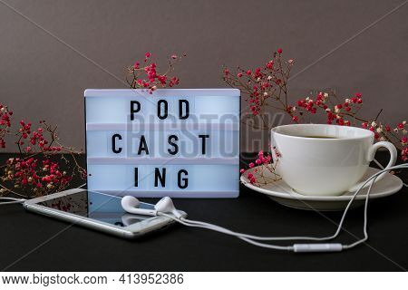 Podcasting Lettering. Headphones Mobile Phone. Dry Pink Flowers Decoration. Workplace. Black Coffee