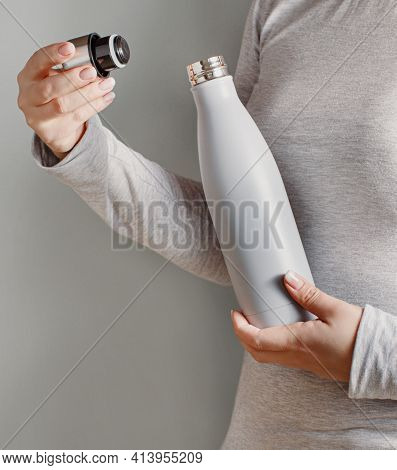 Close Up Of Woman In Grey Tee Holding Grey Insulated Bottle On Grey Background