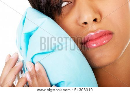 Woman pressing her bruised cheek with a painful expression as if she's having a terrible tooth ache. 