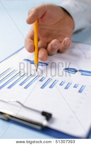 Man Holding A Pencil Working On A Graph