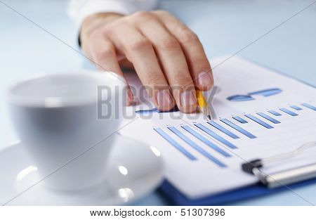 Man Holding A Pencil Working On A Graph