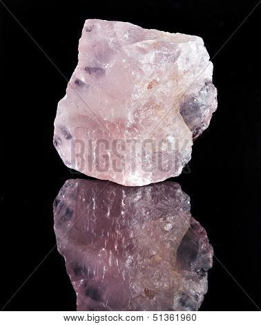 Natural Rose Quartz crystal with reflection on black surface background 