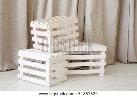 Three white wooden boxes next to linen curtain in bright studio.