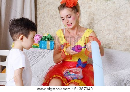 Little boy looks at holiday representative inflating balloon by pump at children party.