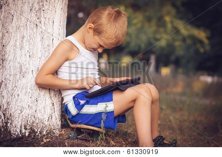 Boy Child Playing With Tablet Pc Outdoor With Summer Nature On Background Computer Game Dependence C
