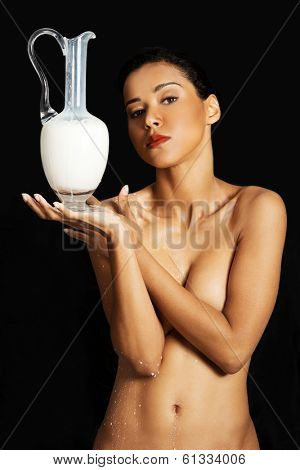 Nude woman is holding a ewer or yug of milk. Spa concept.