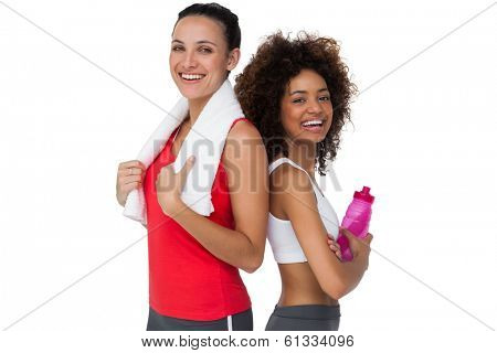 Portrait of two fit young women standing with waterbottle and towel over white background