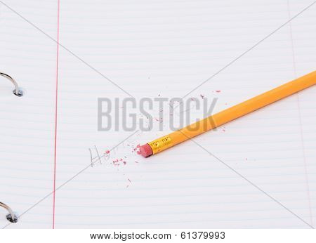 Closeup of a pencil on a notebook page with the word homework partially erased. Back to school concept. 