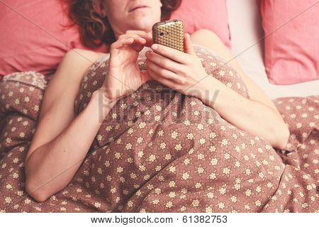 Young Woman Texting In Bed