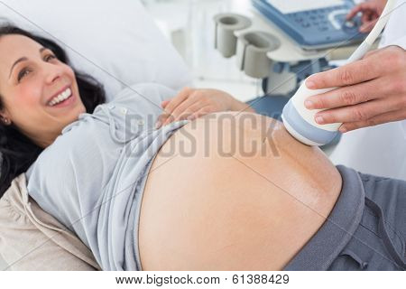 High angle view of smiling pregnant woman receiving ultrasound in hospital