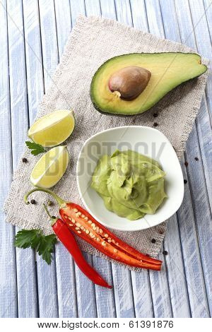 Fresh guacamole in bowl on wooden table