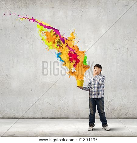 Young boy splashing colorful paint from bucket