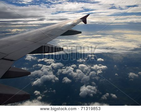 Plain wing at cruising altitude over clouds