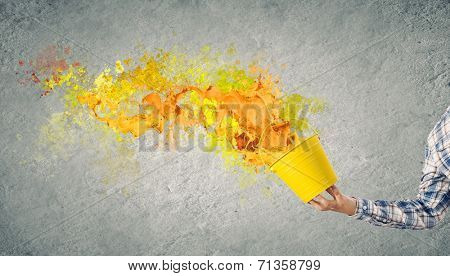 Close up of hand splashing colorful paint from bucket